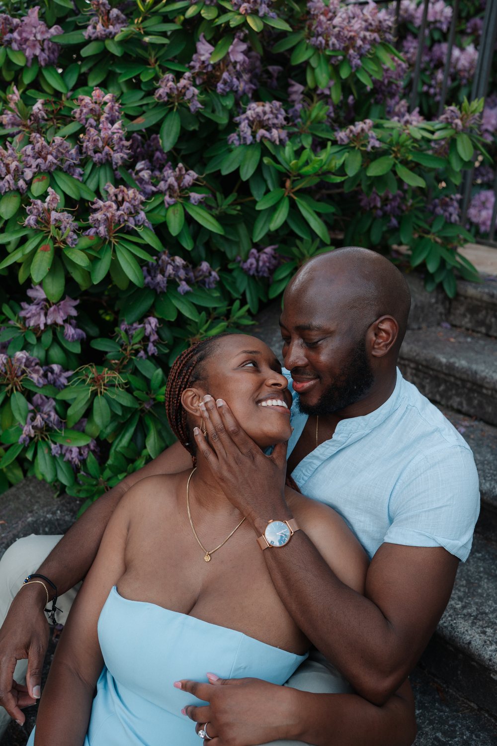 The couple laughing on the garden steps as Sally shows her ring